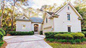 A two-story house with a covered front porch and a driveway leading to the entrance. - Su Casa 5 Bedroom Holiday Home (Hilton Head Island)