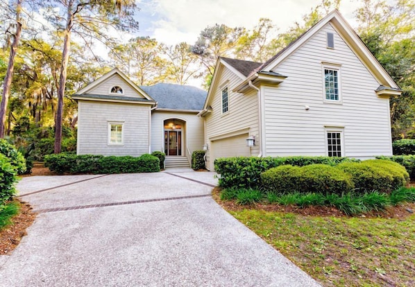 A two-story house with a covered front porch and a driveway leading to the entrance.
