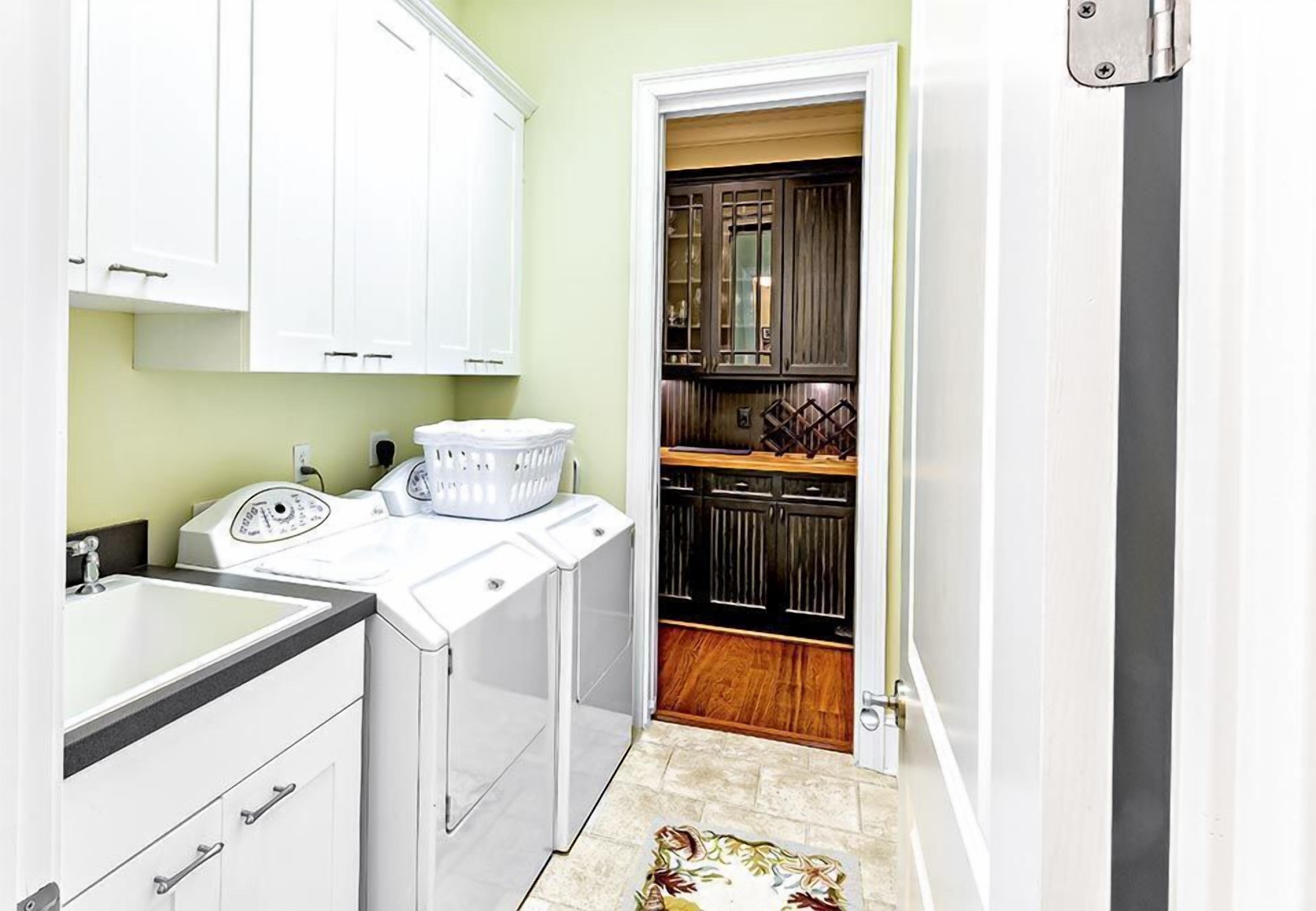 A compact kitchen with white cabinets, a washing machine, and a small countertop.
