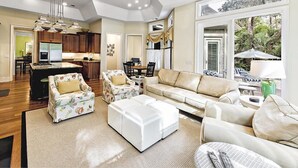 A spacious living room with a large sofa, a coffee table, and a dining area with a table and chairs. - Su Casa 5 Bedroom Holiday Home (Hilton Head Island)
