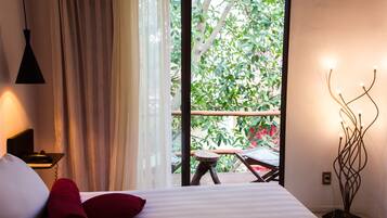 Une chambre d’hôtel avec un lit, une table de chevet avec un téléphone, une fenêtre avec des rideaux et une vue sur la verdure.