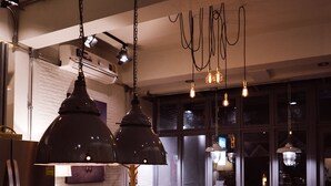 A modern bar area with pendant lighting, a menu board, stools, and a bar counter. - J Poshtel Chiangmai (Chiang Mai)