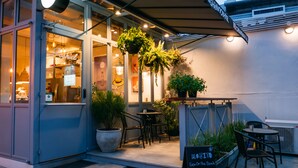 An outdoor seating area with tables and chairs, potted plants, and a sign advertising a special offer. - J Poshtel Chiangmai (Chiang Mai)