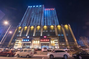 Een hotel met een moderne gevel, meerdere verdiepingen en verlichte signage.