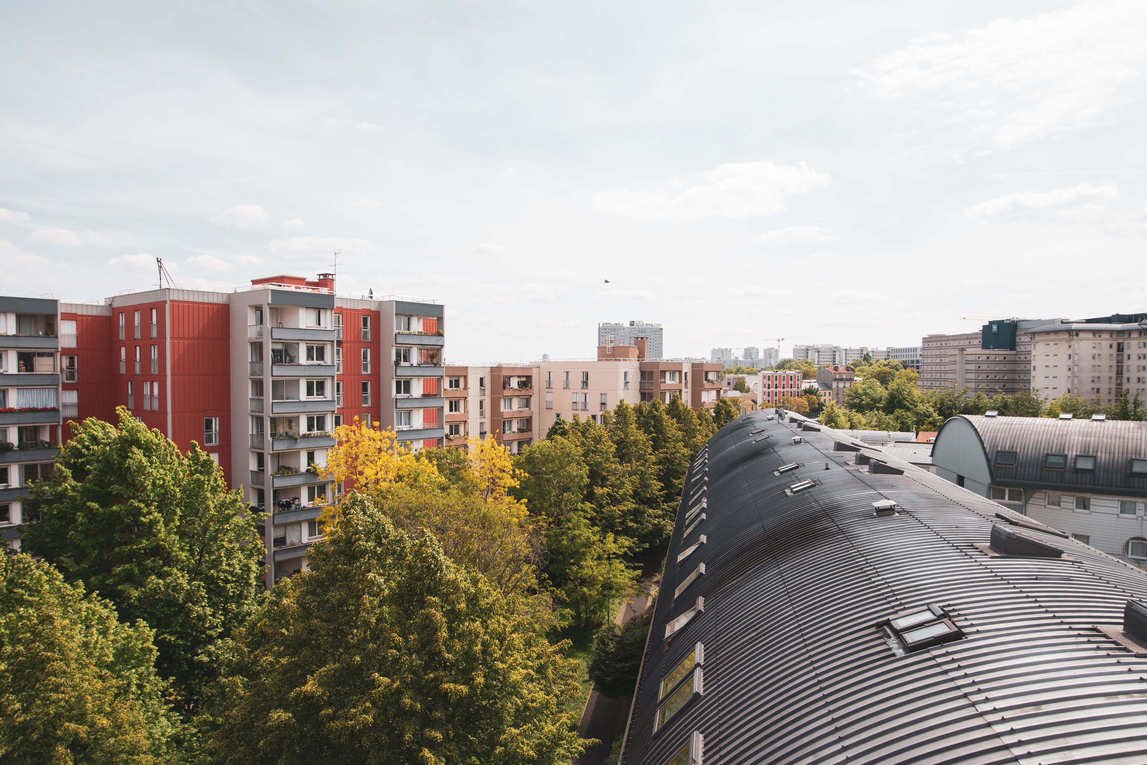 A modern apartment complex with multiple buildings, balconies, and a curved roof structure.