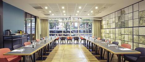 A conference room with long tables, chairs, and a projector on the ceiling.