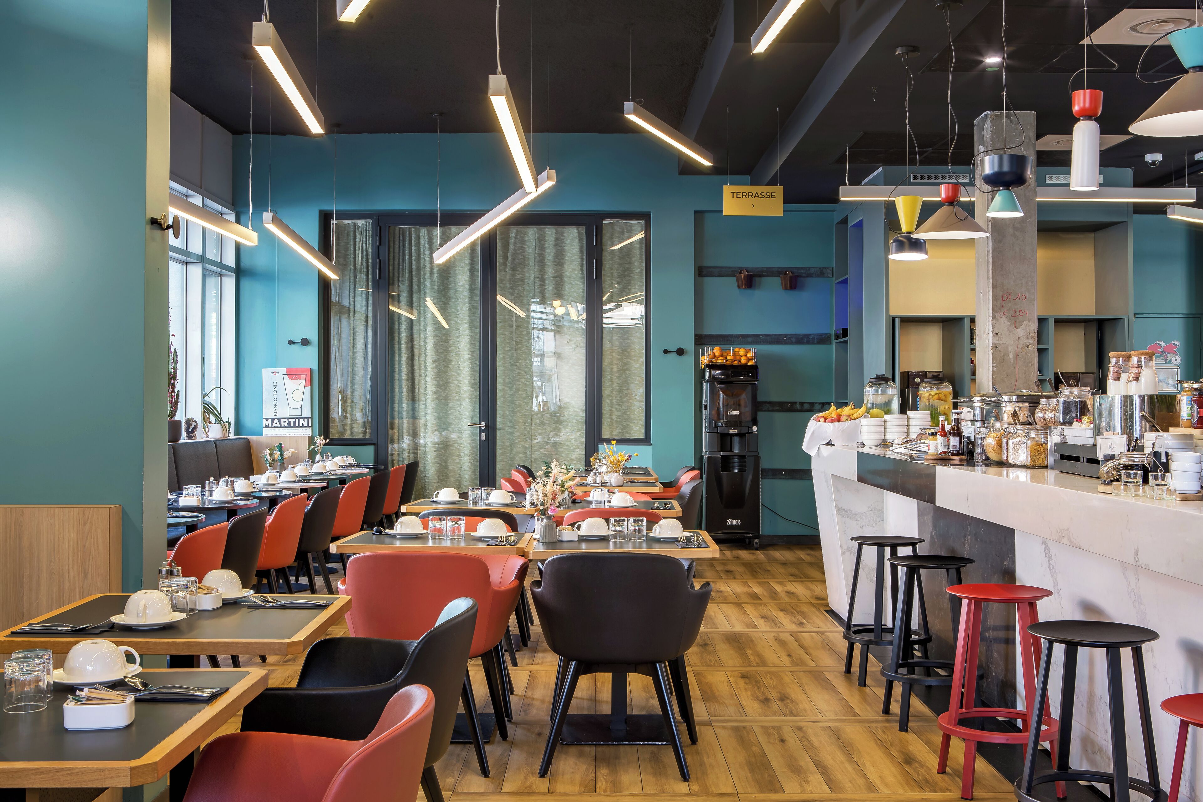 Un restaurante con varias mesas y sillas, una zona de bar y una cocina al fondo.