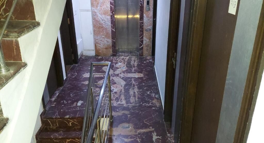 A marble staircase leading to an elevator in a hallway.