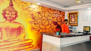 Balcão de recepção com um mural de Buda, uma moldura e um ventilador de teto.