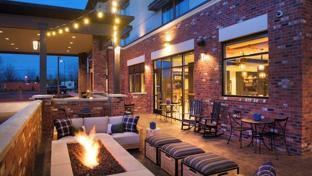 Une terrasse extérieure avec un foyer, des sièges et des tables.
