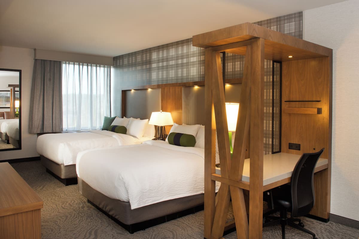 Habitación de hotel con dos camas, un escritorio y una silla.