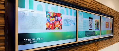 Digitaalinen näyttöseinä, jossa on taideteoksia ja tekstiä, ja jossa erityisesti esitellään Pat Baileyta ja Springhill Suites® Marriott -hotelliketjua.