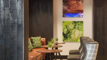 A modern lounge area with a sofa, two small tables with potted plants, and a row of chairs.