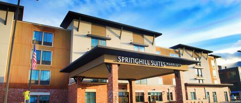 A hotel with a modern design, featuring a covered entrance and a prominent American flag.