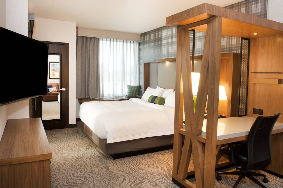 Una habitación de hotel con una cama grande, un escritorio y una televisión.