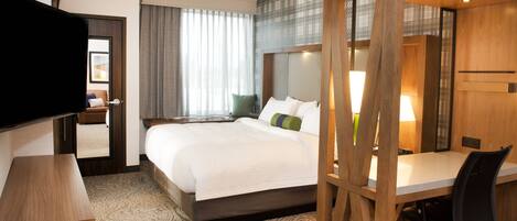 A hotel room with a large bed, a desk, and a television.