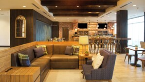 Un intérieur moderne avec un canapé d’angle, un coin bar et un espace repas.