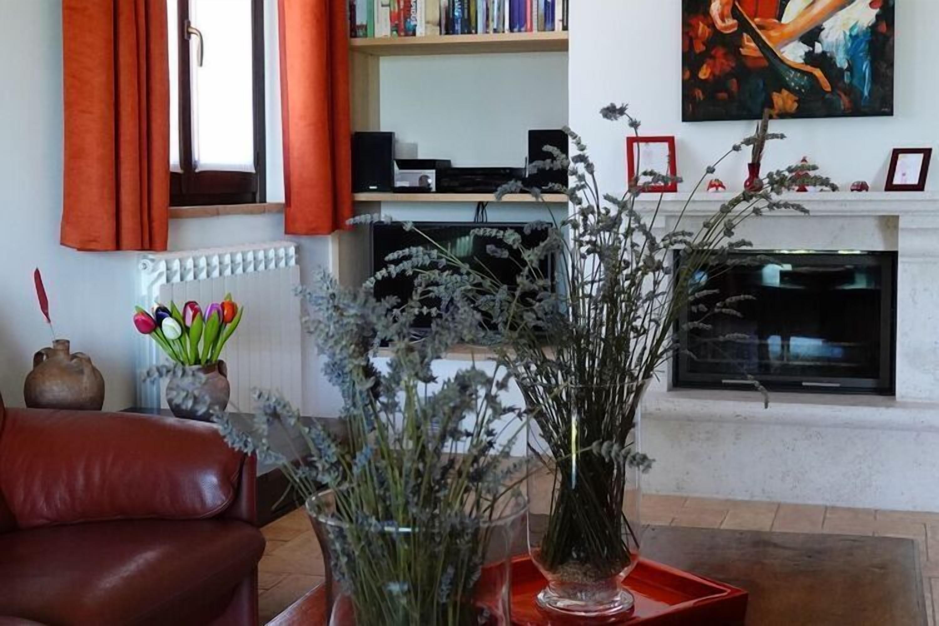 Ein Wohnzimmer mit Kamin, Bücherregal und einem roten Ledersofa.
