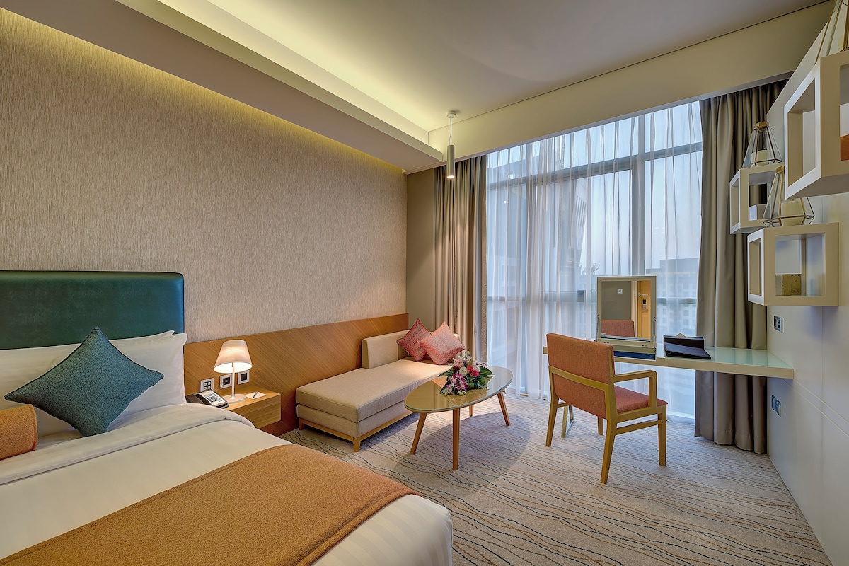 A hotel room with a bed, a sofa, a desk, and a chair.
