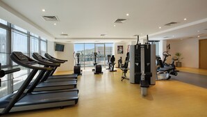 A gym with treadmills, exercise bikes, and weight machines. - Royal Continental Hotel (Dubai)