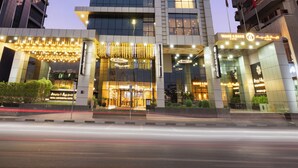 A high-rise hotel with a modern design, featuring a prominent entrance with illuminated signage and a well-lit facade. - Royal Continental Hotel (Dubai)