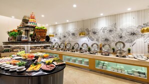 A buffet with various food items and a decorative wall with floral patterns. - Royal Continental Hotel (Dubai)