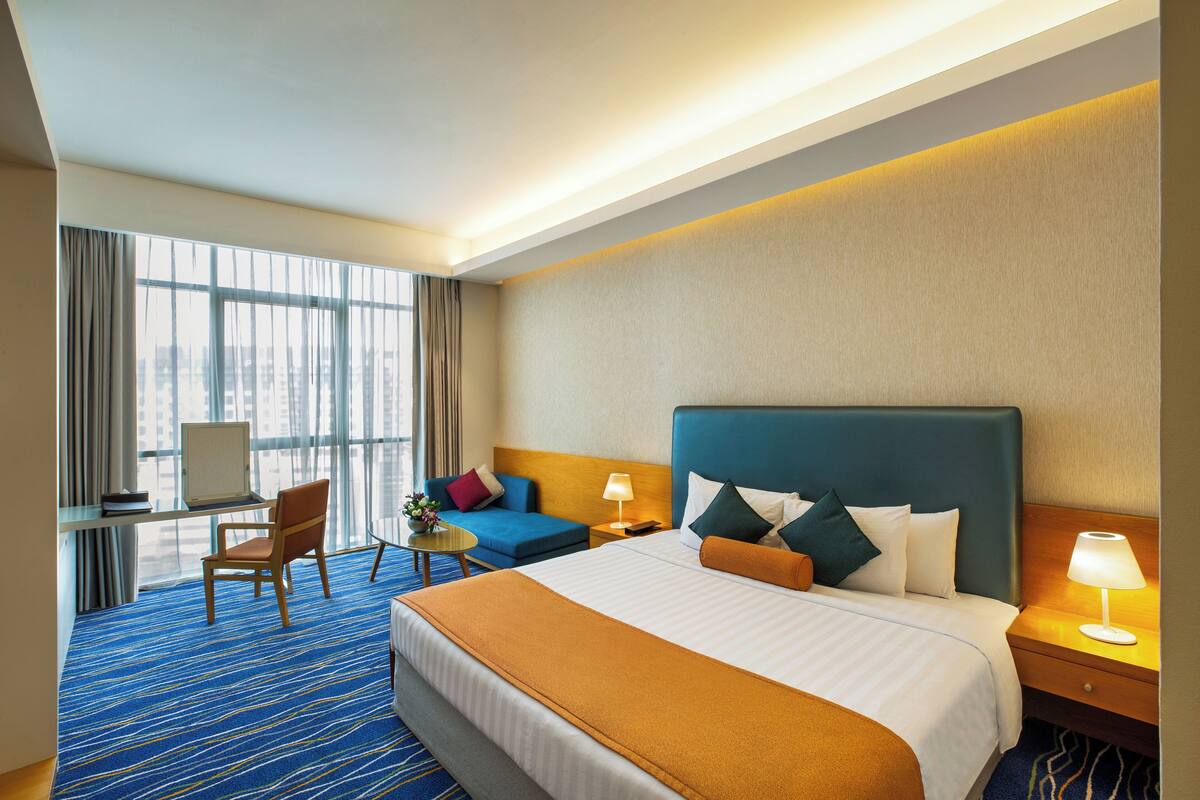 Une chambre d’hôtel avec un grand lit, un bureau avec un ordinateur, une chaise et un canapé.