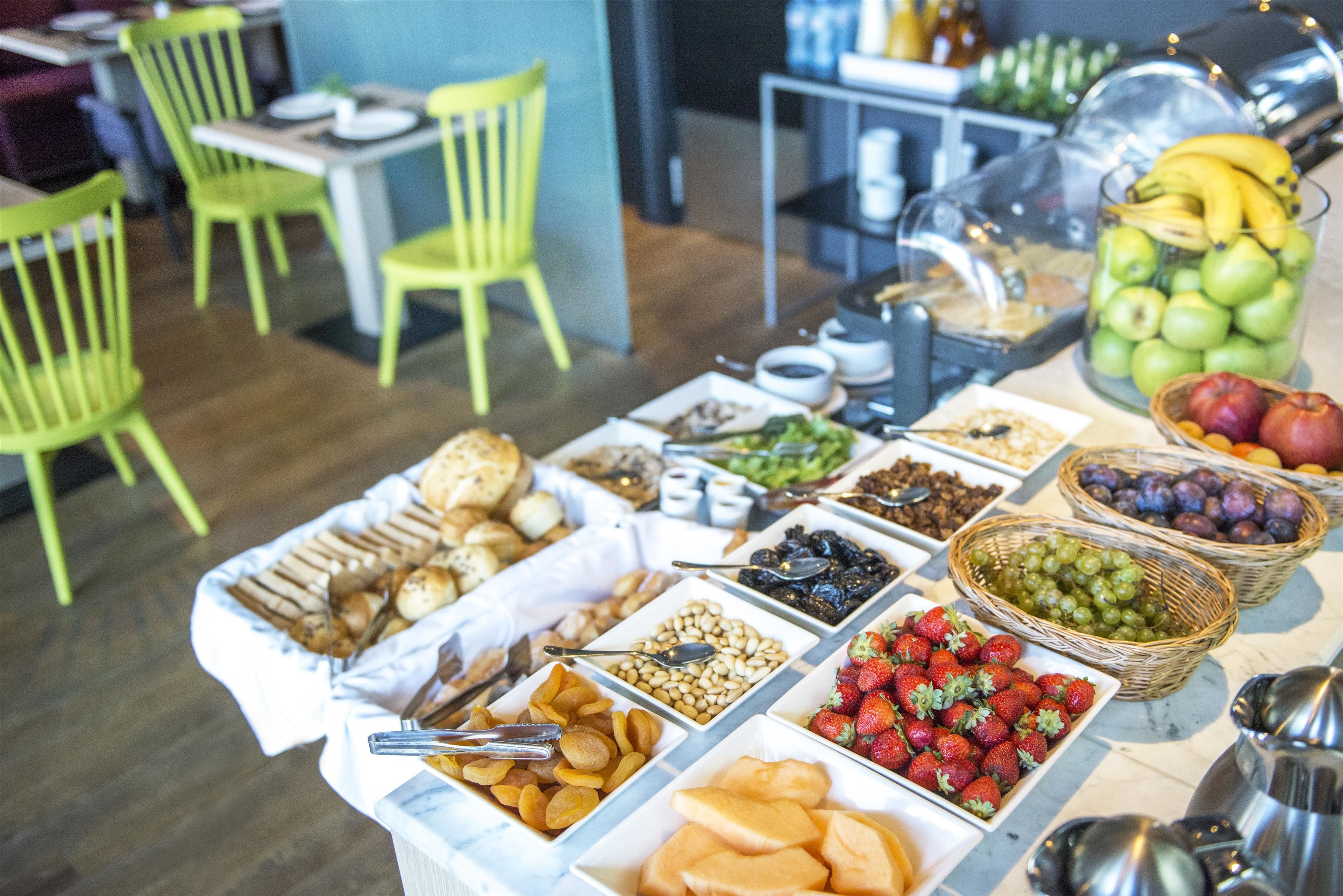 A buffet table with various food items including fruits, nuts, and pastries.