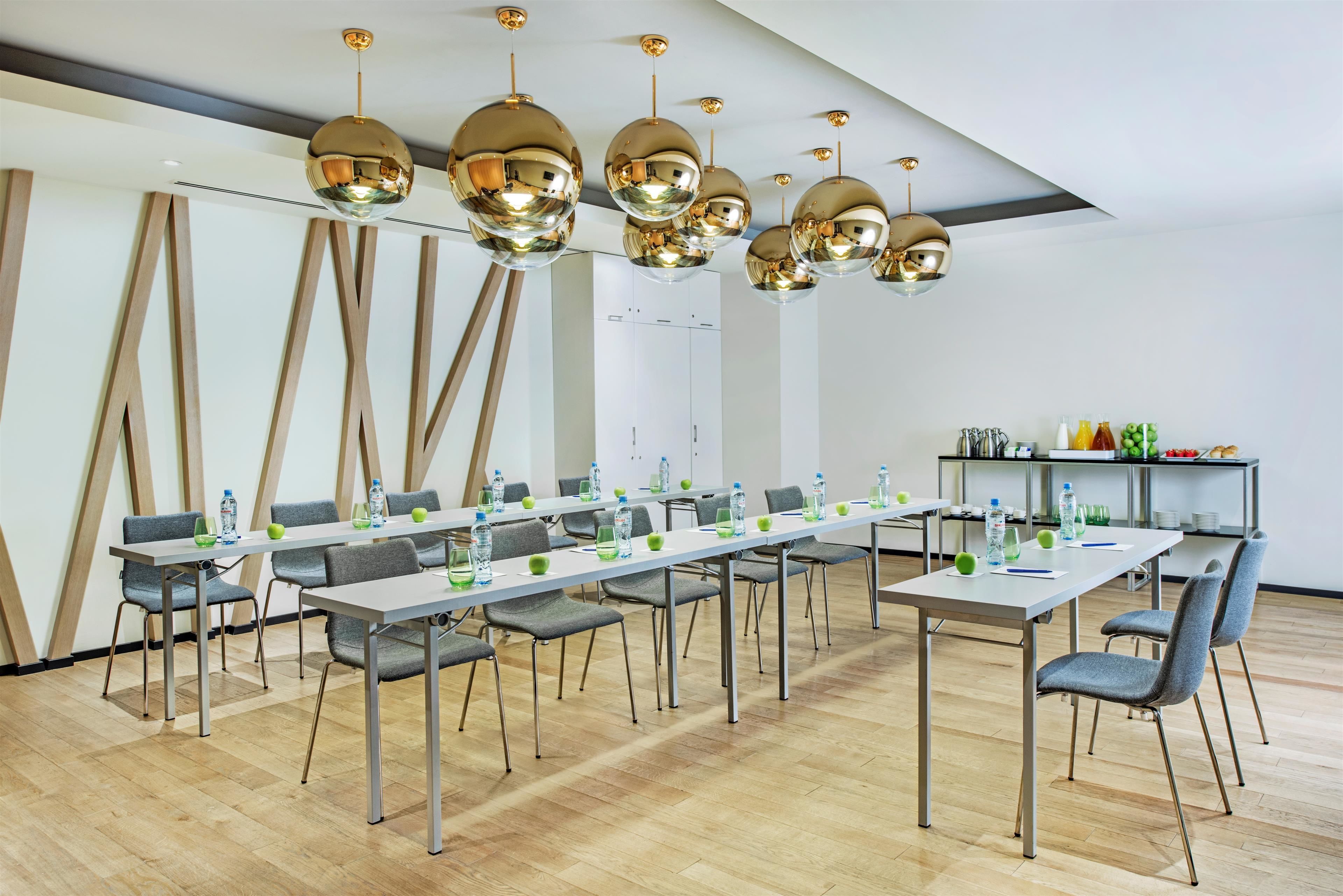 Une salle de conférence dotée d’une longue table, de nombreuses chaises et d’un lustre moderne.