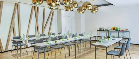 Un salón de conferencias con una larga mesa, varias sillas y una lámpara de araña moderna.