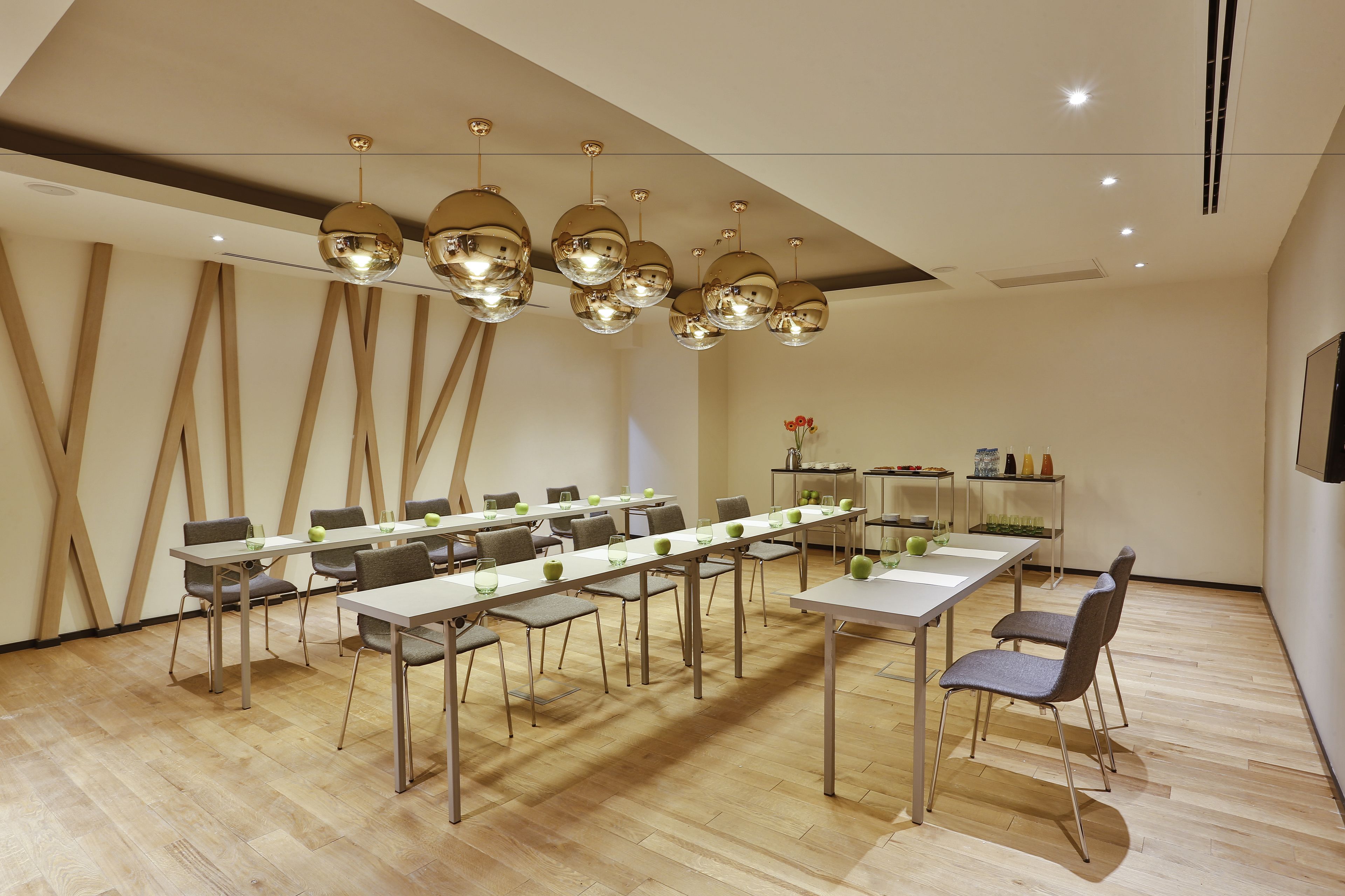 A conference room with a long table, multiple chairs, and hanging spherical light fixtures.
