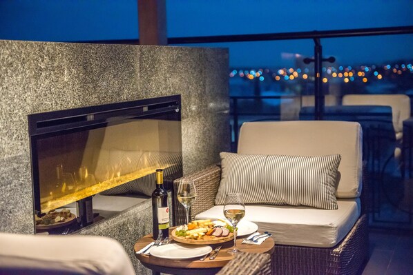 A cozy outdoor seating area with a fireplace, a dining table with plates, glasses, and a bottle of wine. - Best Western Kutaisi City Center (Kutaisi)