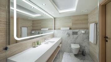 Une salle de bain moderne avec un grand miroir, un lavabo blanc et des murs en marbre.