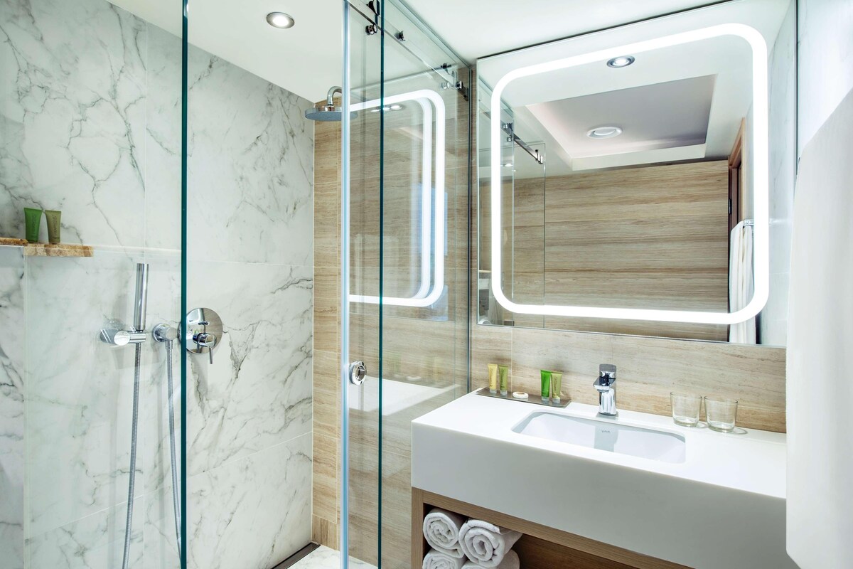A modern bathroom with a glass-enclosed shower, a white sink, and a wooden vanity.