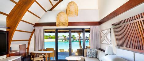 Une chambre d’hôtel dotée d’un grand lit, d’un coin repas, d’une télévision et offrant une vue sur une piscine et une plage.