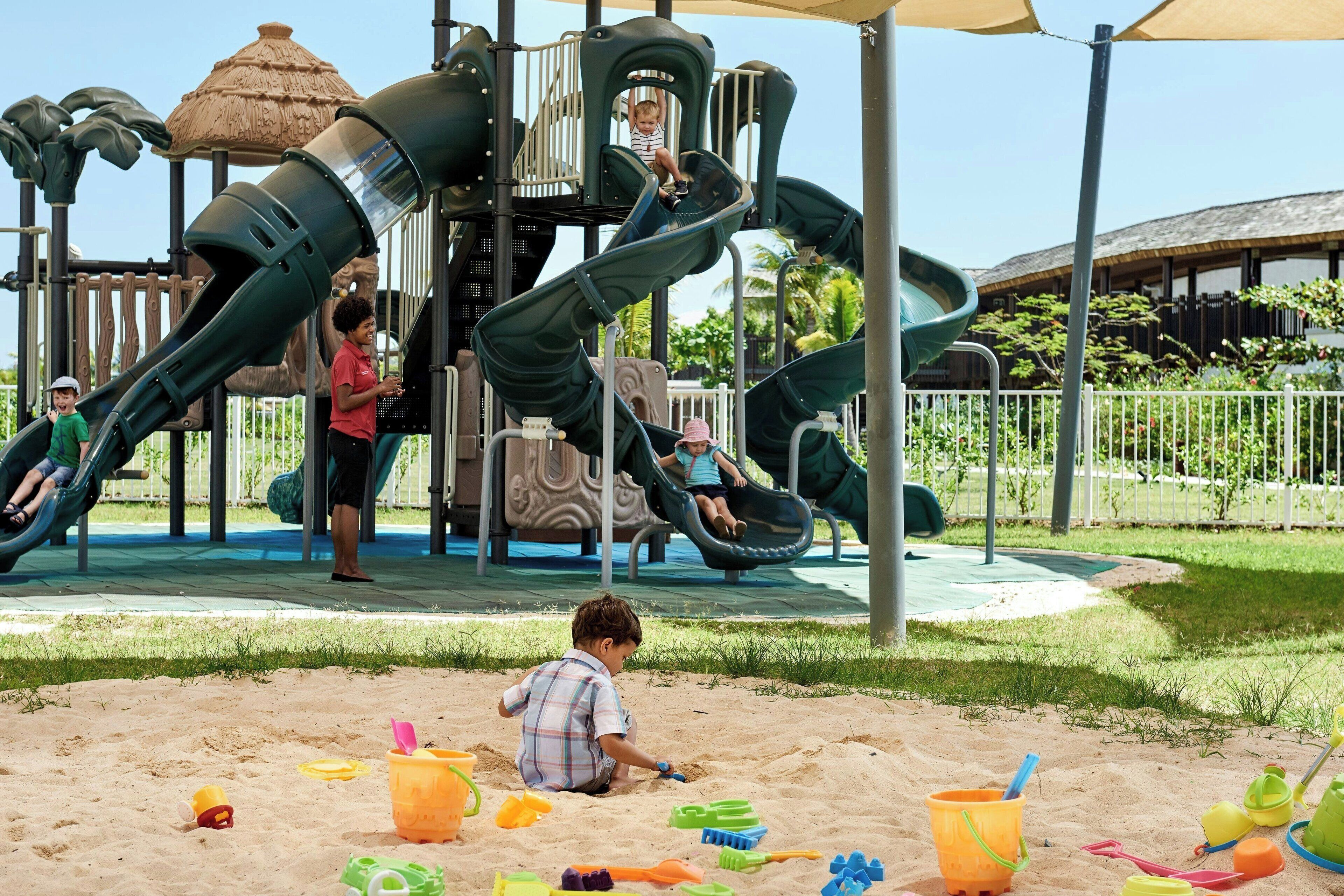 Un parque infantil con toboganes y una zona de arena.