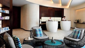 A modern lobby with wicker chairs, a reception desk, and a large white planter.