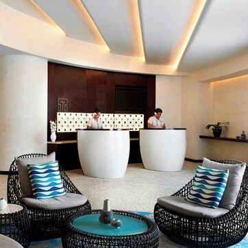 A modern lobby with wicker chairs, a reception desk, and a large white planter.