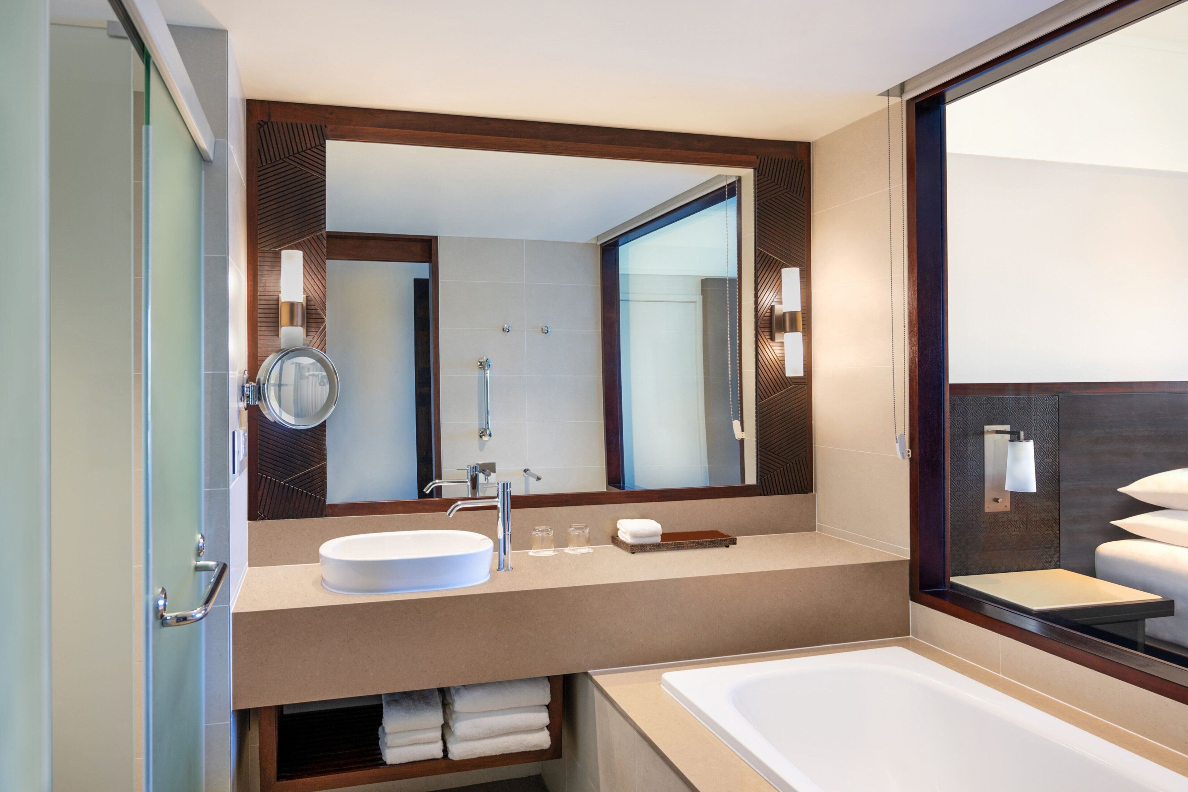 Un baño moderno con un espejo grande, un lavamanos redondo, una bañera y una cabina de ducha de vidrio.