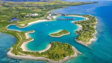 Vue aérienne d’une île-station balnéaire dotée de plusieurs lagons, d’un port de plaisance et d’une végétation luxuriante.