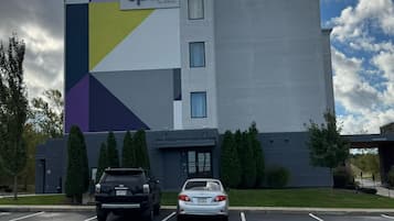Un hotel de diseño moderno, con un amplio estacionamiento y un edificio de fachada geométrica.