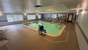 An indoor swimming pool with clear lane markings, a lifeguard chair, and lounge chairs around the pool area. - Spark by Hilton Erie (Erie)