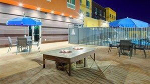 An outdoor patio with a fire pit table, chairs, and blue umbrellas. - Fairfield Inn & Suites by Marriott Bakersfield North/Airport (Bakersfield)