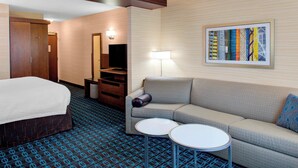 A hotel room with a bed, a sofa, two small tables, a mirror, a lamp, and a framed picture on the wall. - Fairfield Inn & Suites by Marriott Bakersfield North/Airport (Bakersfield)