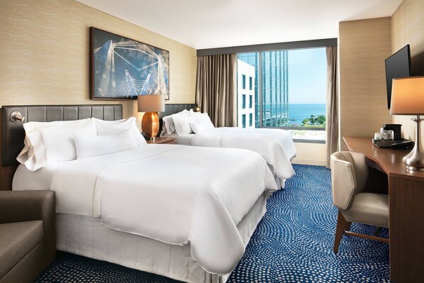A hotel room with two beds, a desk, a chair, a TV, and a large window with a city view. - The Westin Milwaukee (Milwaukee)
