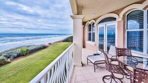 Ein Balkon mit Blick auf das Meer, einem Glastisch und Stühlen.