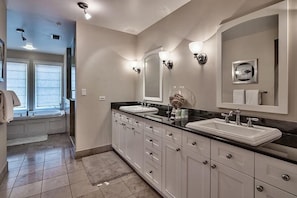 A modern bathroom with two sinks, a large mirror, and a walk-in shower.