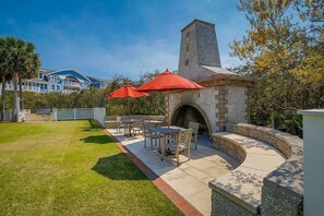 A patio area with a stone fireplace, outdoor furniture, and red umbrellas.