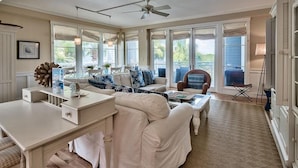 A spacious living room with a large sofa, a coffee table, and a dining area with a white table and chairs.