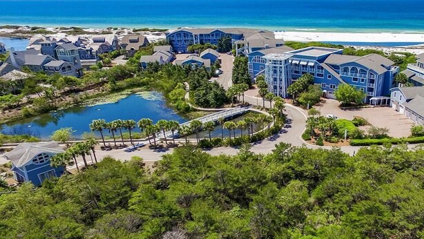 A resort with multiple buildings, a swimming pool, and a beach view.